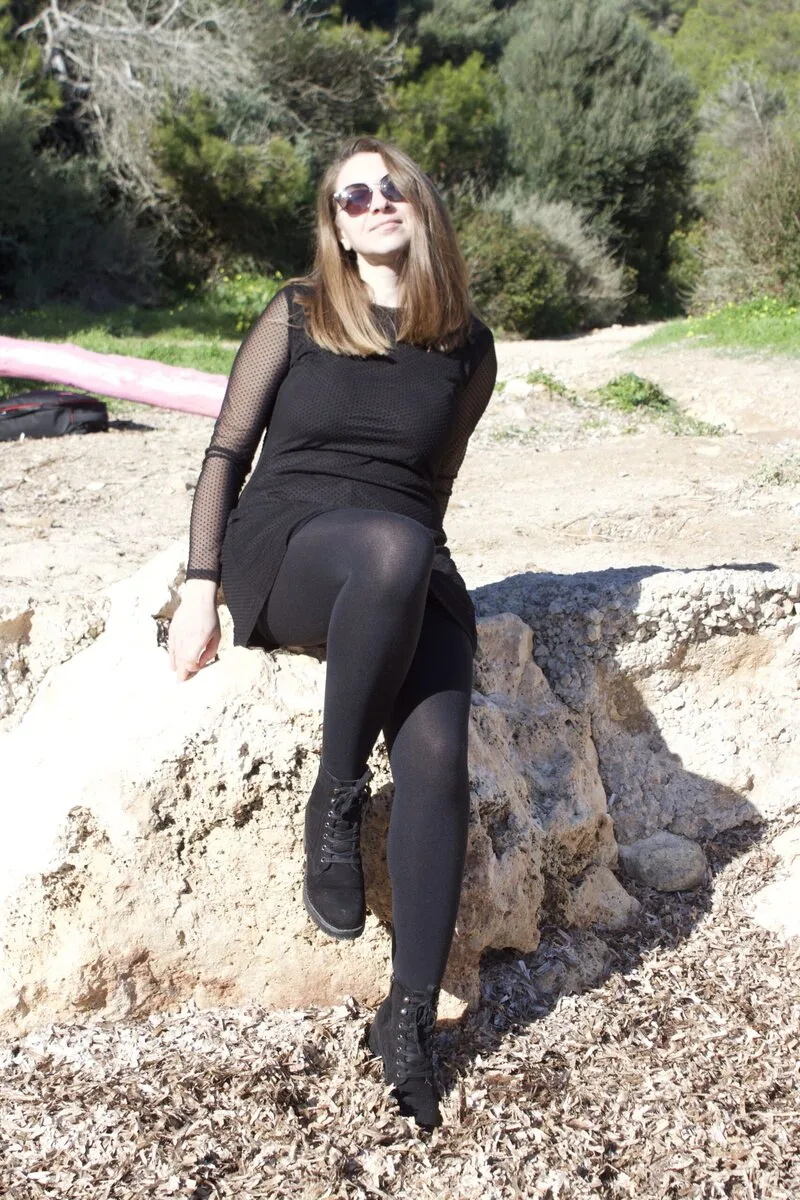 Roxi sentada en unas rocas entre pinos